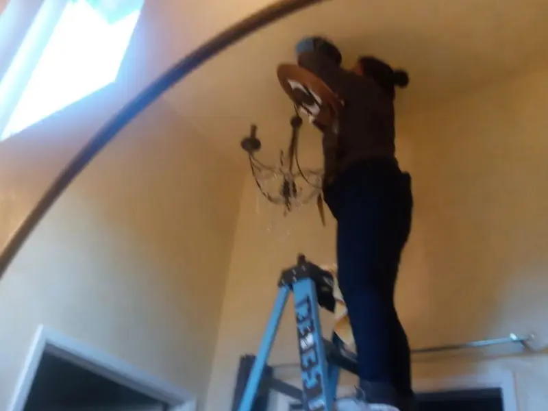 Electrician installing a chandelier in a Magnolia residence